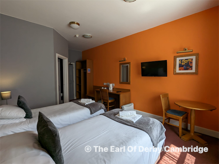 Back of a man at a concert. Hes wearing a beanie hat and a baggy denim jacket with studs. Photo with a purple hue